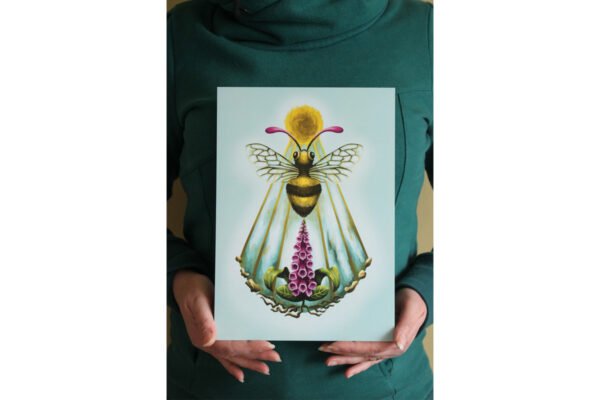 Artist holding A4 Digital Print of Illustration “Sacro Nectare” featuring a honey bee with sun and foxglove plant (digitalis)