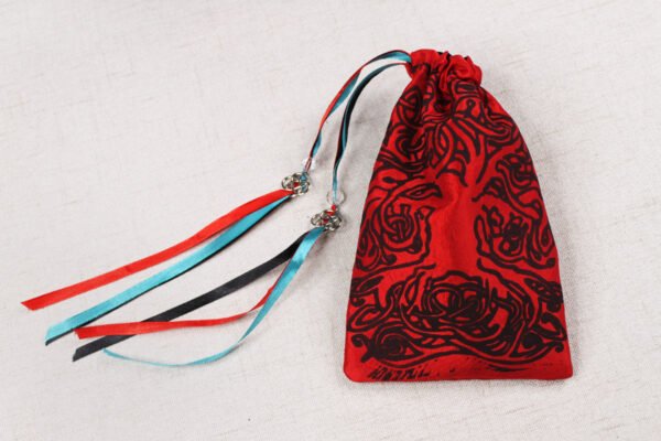 Red handprinted fabric drawstring bag with spiralling tree print closed with colourful ribbons and beads splayed out