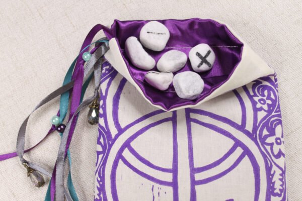 Unbleached Cotton Chalice Well pouch with purple poly-satin lining, rune stones that spell Imogen are sitting in the pouch