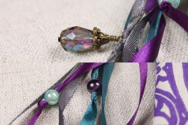 Close Up of Chalice Well Lid Pouch showing grey, teal and purple ribbons, blue and purple plastic beads and glass bead charms