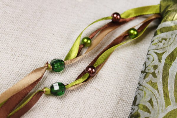 Close Up of Chalice Well Pouch showing green, brown and taupe ribbons, clear green pearlesque green and brown plastic beads