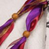 Close Up of Legendary Medieval Heraldic Dragon Pouch showing Burgundy Red, Purple and Gold ribbons, and wooden beads.