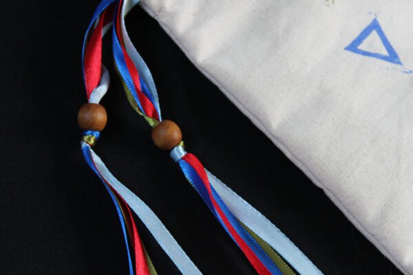 Close Up of Four Element (Four Temperament) Pouch showing red, electric blue, light blue and green ribbons, and wooden beads