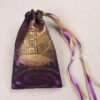 Closed purple handprinted fabric drawstring bag with Glastonbury Tor and white spring print with ribbons and beads splayed