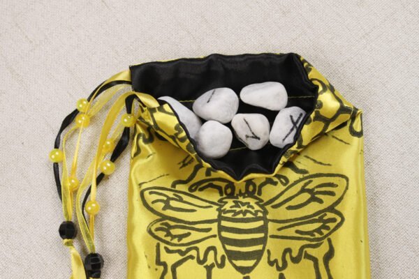 Yellow poly-satin bee pouch with black poly-satin lining, white rune stones that spell Imogen are sitting in the pouch