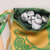 Gold poly-satin Selkie Beast pouch with dark green poly-satin lining, white rune stones spelling Imogen are sitting in pouch