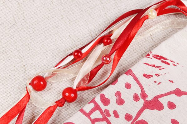 Close Up of Toadstool Pouch showing red and cream ribbons, iridescent pearl cream and red plastic beads and red wooden beads