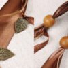 Close Up of Druid Tree Pouch showing dark brown and taupe ribbons, wooden beads and brass coloured metal leaf charms