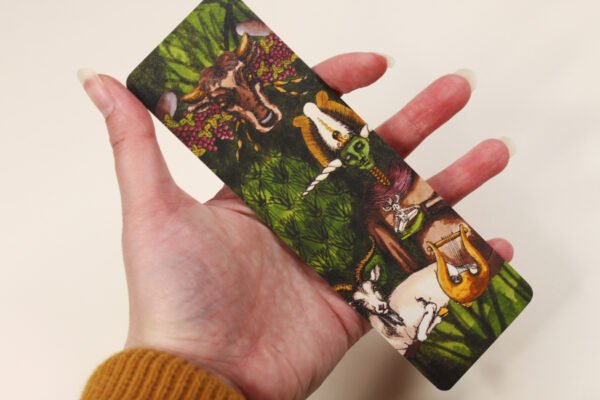 Artist holding Bookmark of Illustration “Horned Gods” featuring Osiris, Pashupati, Celtic Cernunnos, Greek Dionysus and Pan