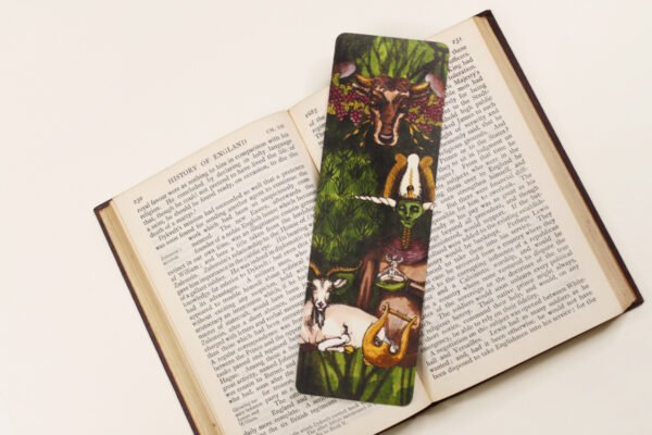 Horned God Myths bookmark with green, golden yellow and plum purple colours on a black and white text page of open book