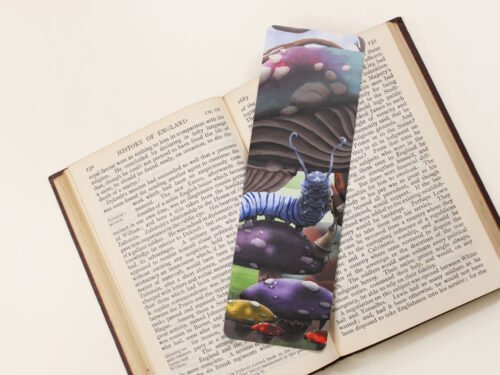 Caterpillar of Wonderland, bookmark with large magical toadstools and mushroom on a black and white text page of open book