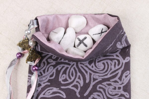 Purple Cotton knotwork tree pouch with light purple taffeta lining, white rune stones that spell Imogen sitting in the pouch