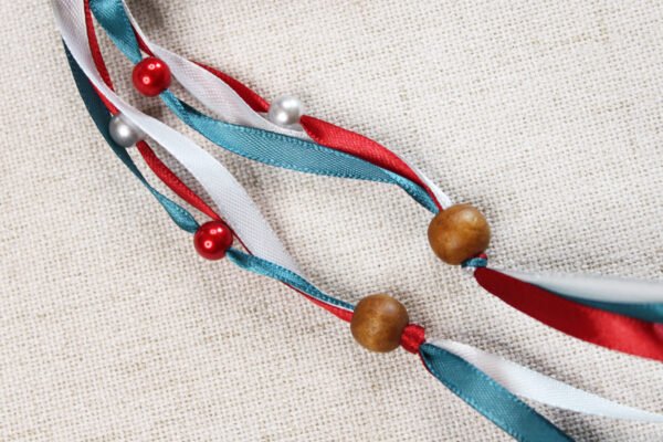 Close Up of Vikings Raven Pouch showing red, white and teal ribbons, pearl silver and red plastic beads and wooden beads