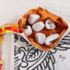 White cotton bennu myrrh leaf pouch with orange poly-satin lining, white rune stones that spell Imogen are in the pouch