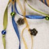 Close Up of spiral, pentagram and rosebuds Pouch showing green, gold, blue ribbons, pearlesque plastic beads and metal charms