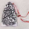 Closed white handprinted fabric drawstring bag with Pentagram, spiral and roses print with ribbons and beads splayed out