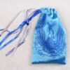 Closed blue handprinted fabric drawstring bag with Phoenix born from the ashes print with ribbons and beads splayed out