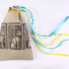 Taupe handprinted fabric drawstring bag with Cat Goddess print closed with colourful ribbons and beads splayed out