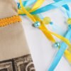 Close Up of Bastet Pouch showing turquoise and yellow ribbons, iridescent yellow and pearl blue plastic beads and brocade