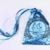 Blue handprinted fabric drawstring bag with Moon Gate and Stars print closed with colourful ribbons and beads splayed out