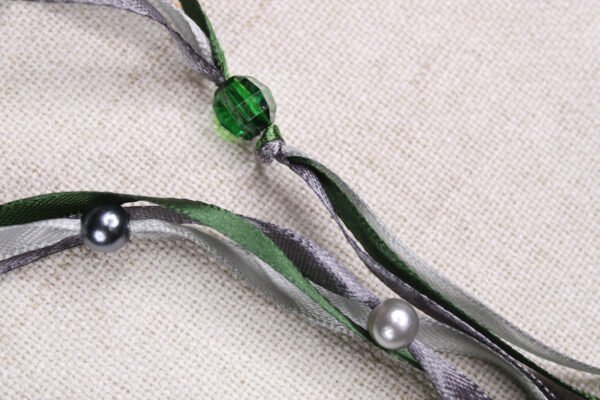 Close Up of Moon Pouch showing green, grey and silver ribbons, clear green and pearly silver plastic beads
