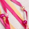 Close Up of Moon Pouch showing pink and gold coloured ribbons, iridescent pink, pearly pink and magenta plastic beads